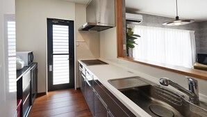 Eine moderne Küche mit Spüle aus Edelstahl, eingebautem Ofen und einem Fenster mit Jalousien.