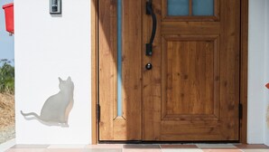 Eine Holztür mit Glasschieber, eine Katzenkontur an der Wand und ein roter Briefkasten.