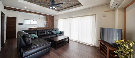 A modern living room with a sectional sofa, a coffee table, and a TV on a wooden stand.
