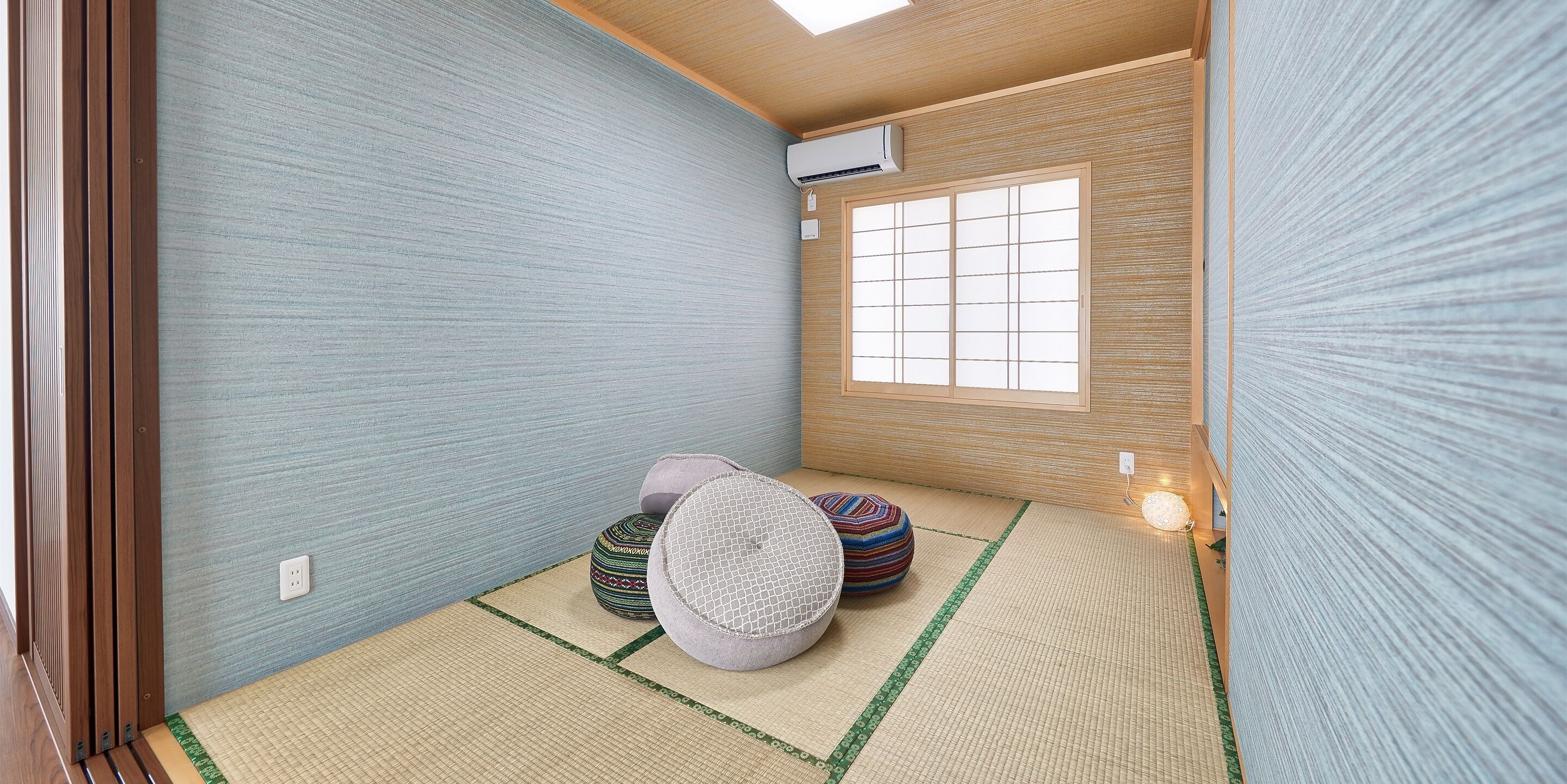 A traditional Japanese room with tatami flooring, a shoji screen, and a small tatami mat with cushions.
