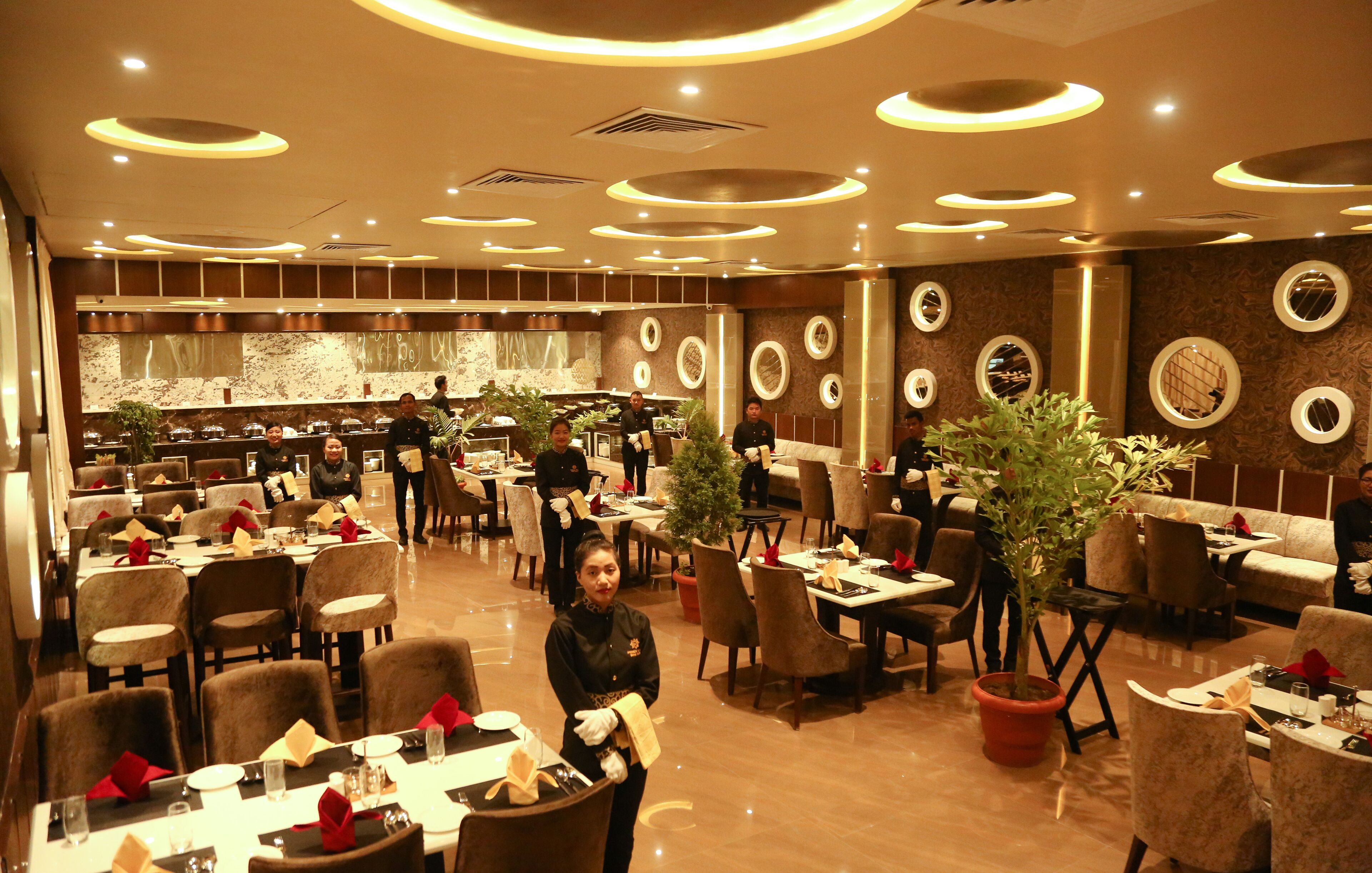 A spacious restaurant with multiple dining areas, round tables, and chairs.