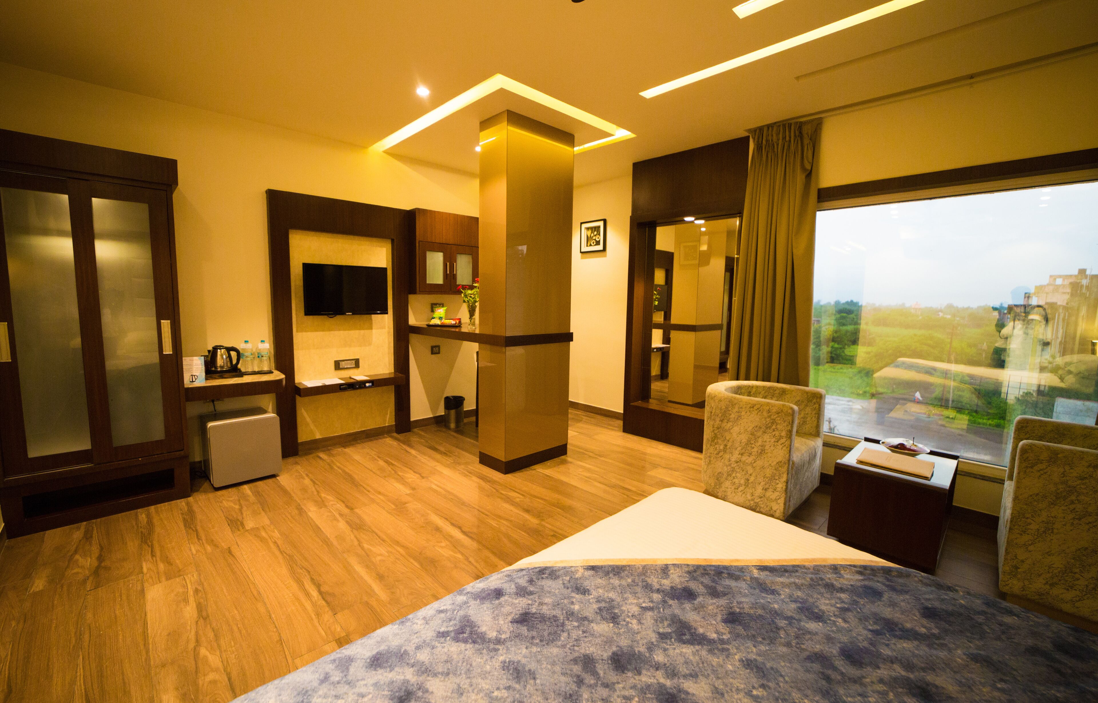A hotel room with a bed, a desk, a chair, a television, and a window with a view of the outdoors.
