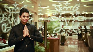 A person in a black suit standing in a hotel lobby with a decorative glass partition featuring leaf patterns. - Hotel Prince Viraj (Jabalpur)
