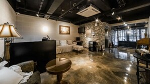 Un espace de détente moderne avec un mur en pierre, un canapé, une table et un téléviseur fixé au mur.
