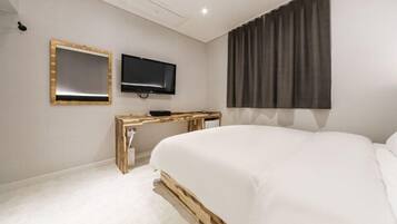 A bedroom with a bed, a TV, and a desk.