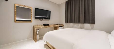 A bedroom with a bed, a TV, and a desk.