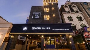 L’entrée d’un hôtel, avec une enseigne indiquant « Hôtel Vallas », comprenant un petit hôtel et une maison d’hôtes.