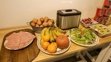 A kitchen counter with various food items including eggs, bananas, apples, and a salad.