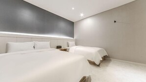 Une chambre d’hôtel moderne avec deux lits, une grande fenêtre et un design minimaliste.