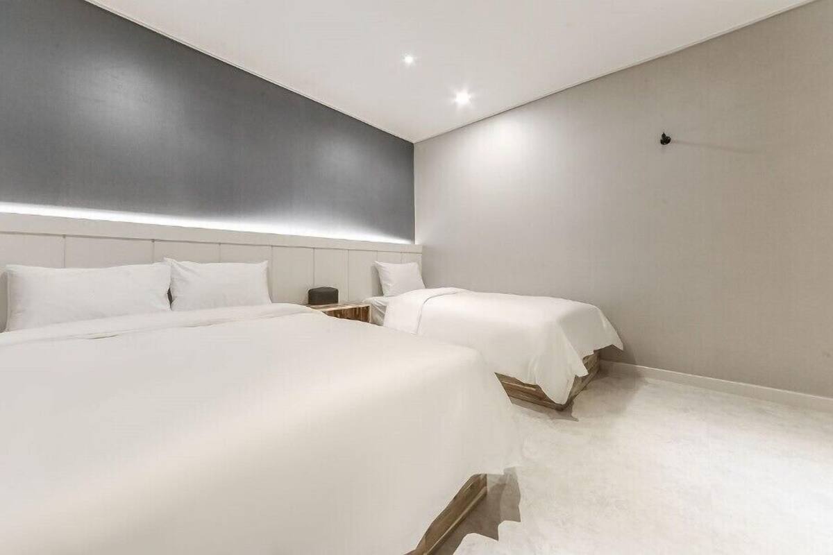Een moderne hotelkamer met twee bedden, een groot raam en een minimalistisch design.