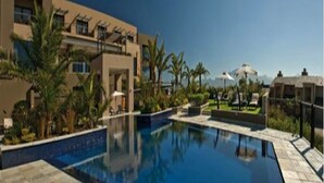 Ein Resort mit Swimmingpool, Palmen und Blick auf die Berge.