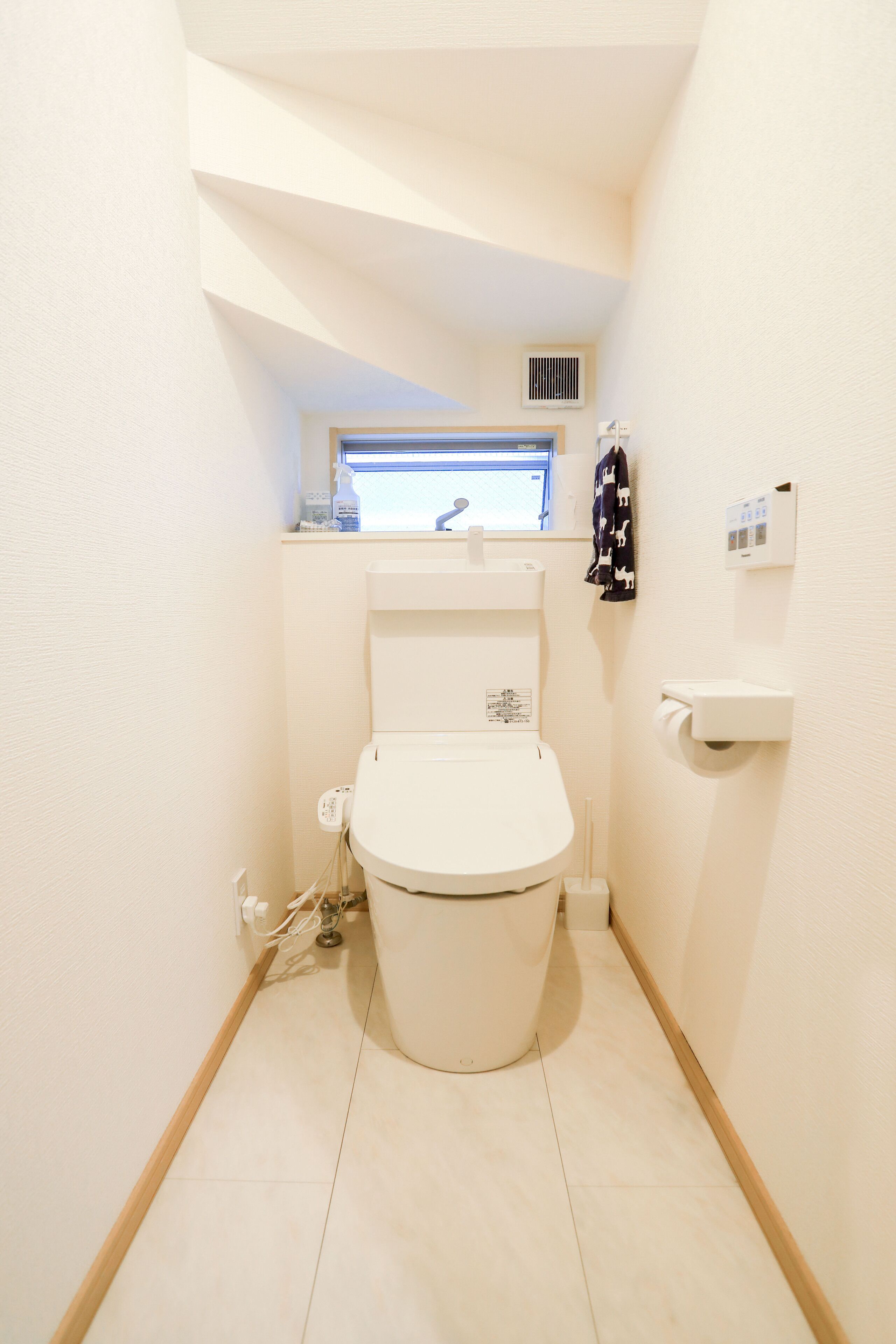 Ein kleines, kompaktes Badezimmer mit Toilette, Waschbecken und einem Fenster über dem Waschbecken.