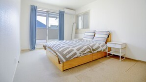 Une chambre à coucher avec un lit en bois, une table de chevet, une fenêtre avec des rideaux et un luminaire au plafond.