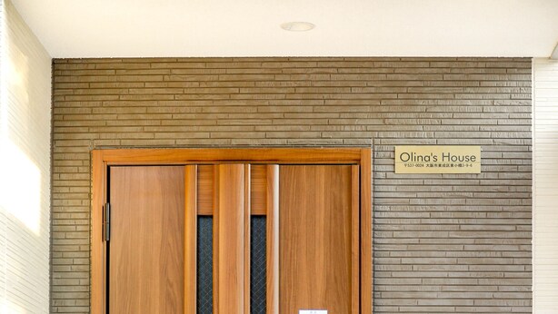 Une porte en bois avec une plaque portant l’inscription « La maison d’Olina » et un clavier de sécurité.
