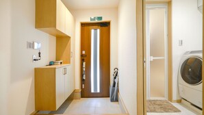 Un couloir avec un meuble en bois, une porte dotée d’un luminaire et un lave-linge.