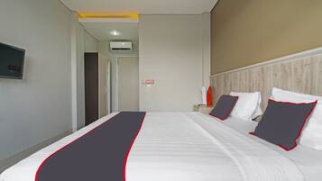 A hotel room with a large bed, a nightstand, and a TV mounted on the wall.