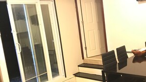 A dining area with a table and chairs, a sliding glass door, and a staircase leading to another level. - Convenient and clean studio near the beach and Newport. (Middletown)