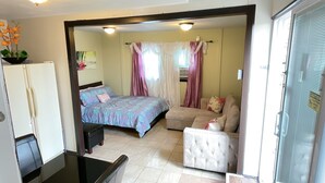 A bedroom with a bed, a sofa, a chair, and a refrigerator. - Convenient and clean studio near the beach and Newport. (Middletown)
