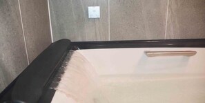 A bathtub with a handle, a tiled wall, and a power outlet. - Hakuba Hokujo (Hakuba)