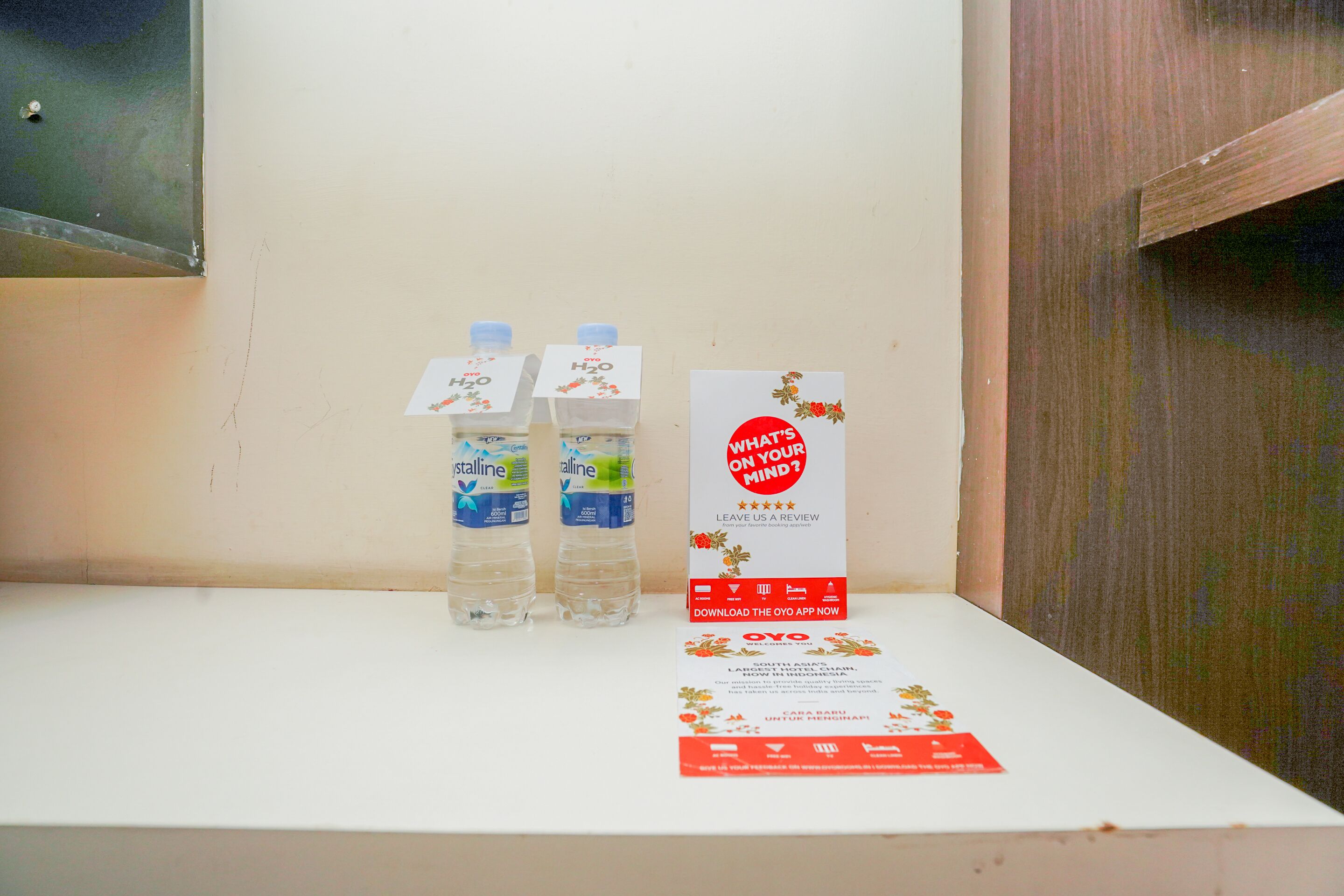 A white shelf with three water bottles labeled 'Oyo' and a red card with 'WHAT'S ON YOUR MIND?' text.