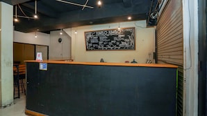 Een restaurantinterieur met een zwarte toonbank, een krijtbordmenu en hangende lampen.