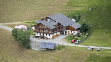 Ein großes, zweistöckiges Holzhaus mit geneigtem Dach, einem Steinfundament und einer Solaranlage.