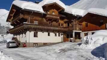 Eine Holzchalet mit Balkon, umgeben von schneebedeckten Bergen.