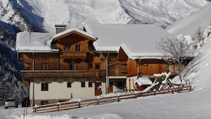 Un chalet en bois doté d’un balcon, entouré de montagnes enneigées.