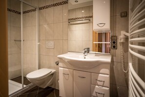 Ein Badezimmer mit Dusche, Toilette, Waschbecken und Spiegel.