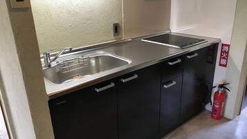 Uma cozinha compacta com uma pia de aço inoxidável, fogão embutido e armários pretos.