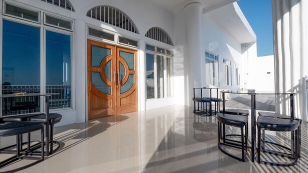 Un interior luminoso y soleado con una puerta de madera grande, varias ventanas y un suelo pulido.