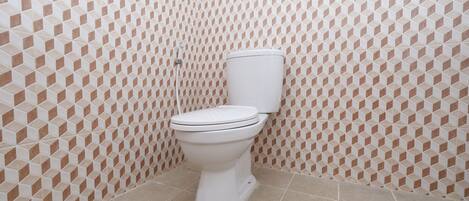 A bathroom with a toilet, tiled walls, and a tiled floor.