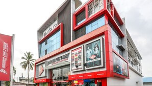 A multi-story building with a prominent red and white facade, featuring large glass windows and several advertisements. - Collection O 30002 Bhel Hyderabad (Sangareddi)