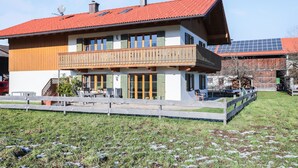 A two-story building with a balcony, solar panels, and a fenced yard. - Cosy Apartment "Bergblick" with Garden, Terrace & Wi-Fi; Parking Available (Bad Heilbrunn)