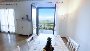 A dining area with a table set for two, a pineapple centerpiece, and a view of a cityscape through a glass door. - Villa Bel Panorama - a beautiful house with an amazing sea view (Portoferraio)