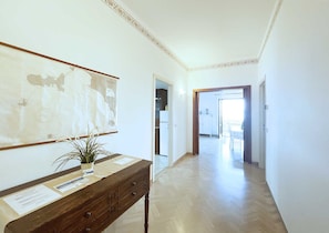 A hallway with a wooden desk, a map on the wall, and a potted plant.