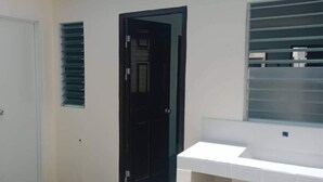Una stanza con una porta bianca, una porta nera e una finestra con persiane.