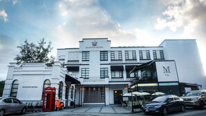 Un hotel de fachada clásica, una cabina telefónica roja y un letrero de café.
