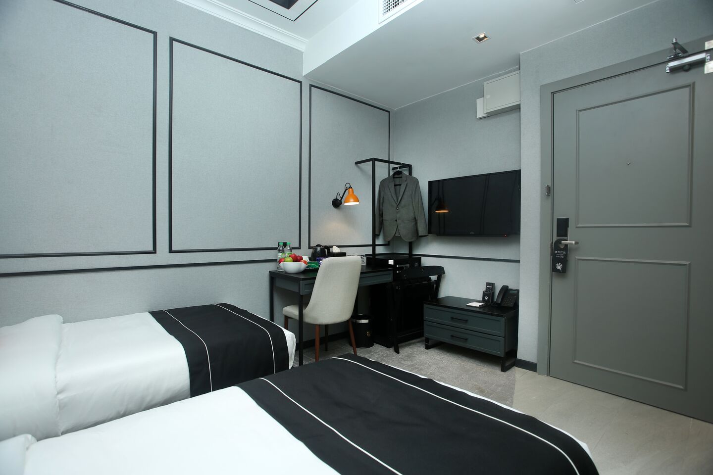 A hotel room with a bed, a desk, a chair, a TV, and a wardrobe.