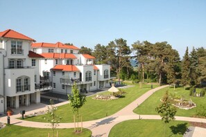 A multi-story building with a red-tiled roof, surrounded by a well-maintained lawn and trees. - Haus Meeresblick FeWo Strandlöper C 2.02 Ref. 134796 - FeWo Strandlöper C 2.02 (Baabe)