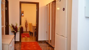 Un couloir d’hôtel avec un espace repas, une moquette rouge et un réfrigérateur.