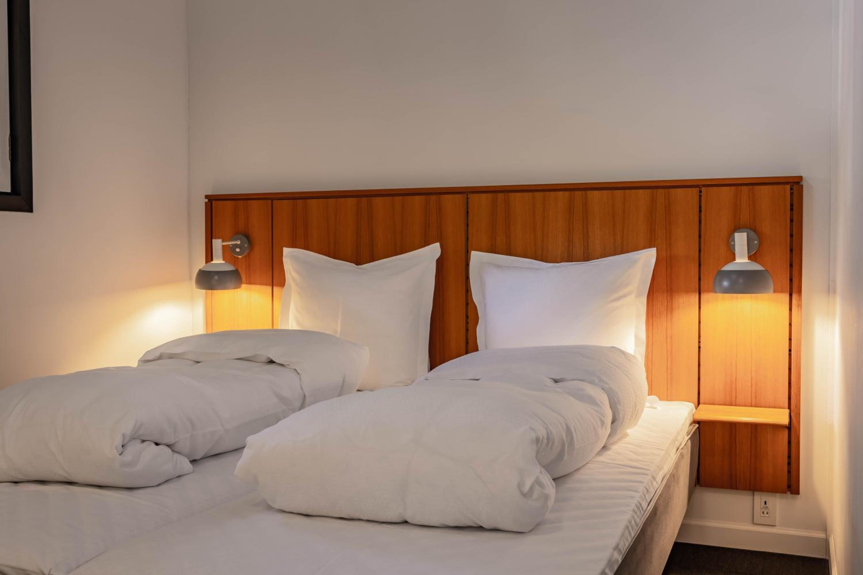 A double bed with two pillows and two bedside lamps.