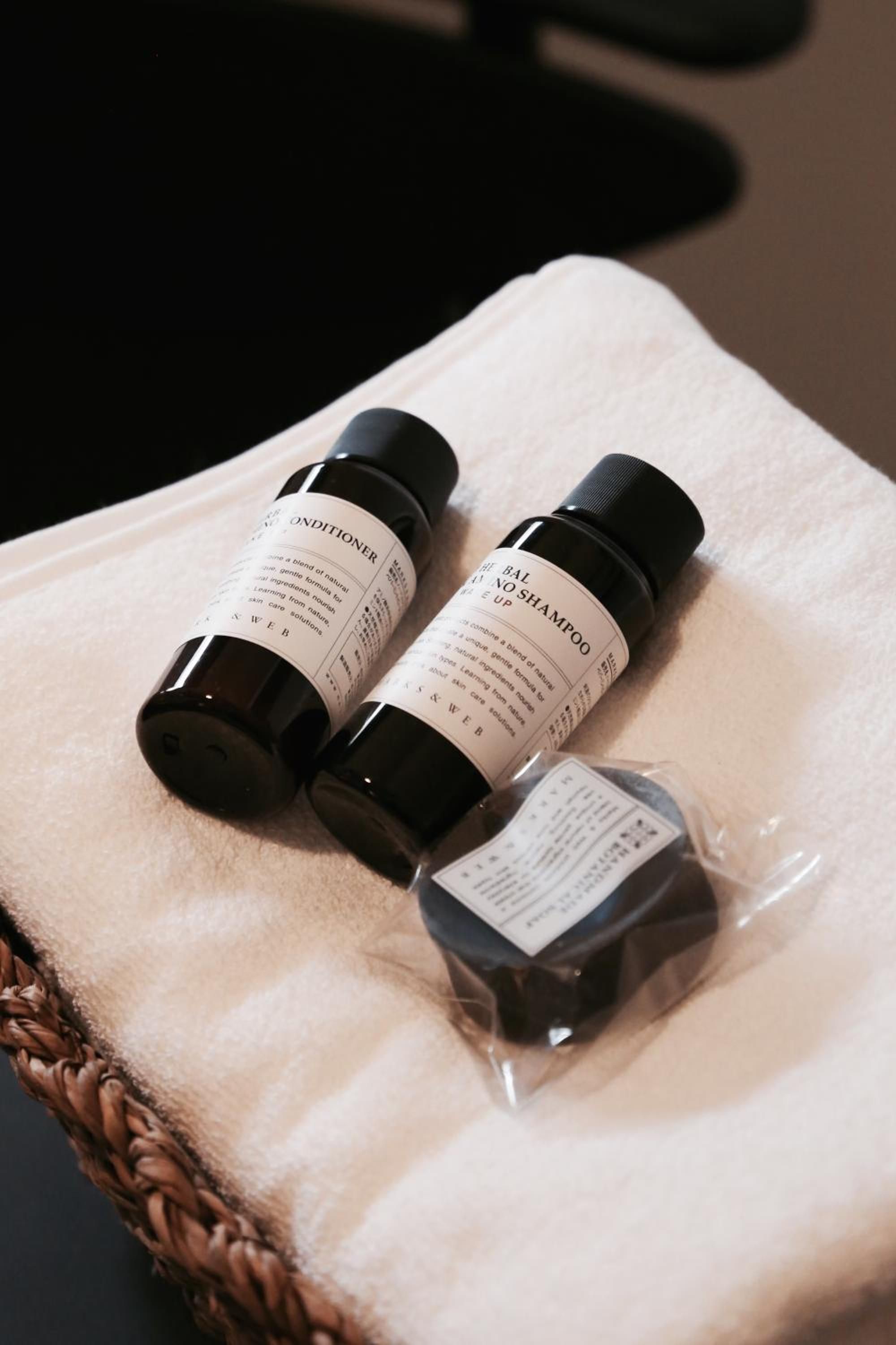 Three bottles of hair care products on a white towel.