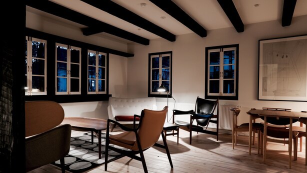 A room with a wooden floor, a dining table with chairs, a sofa, and large windows with black frames. - House of Finn Juhl Hotel Hakuba (Hakuba)
