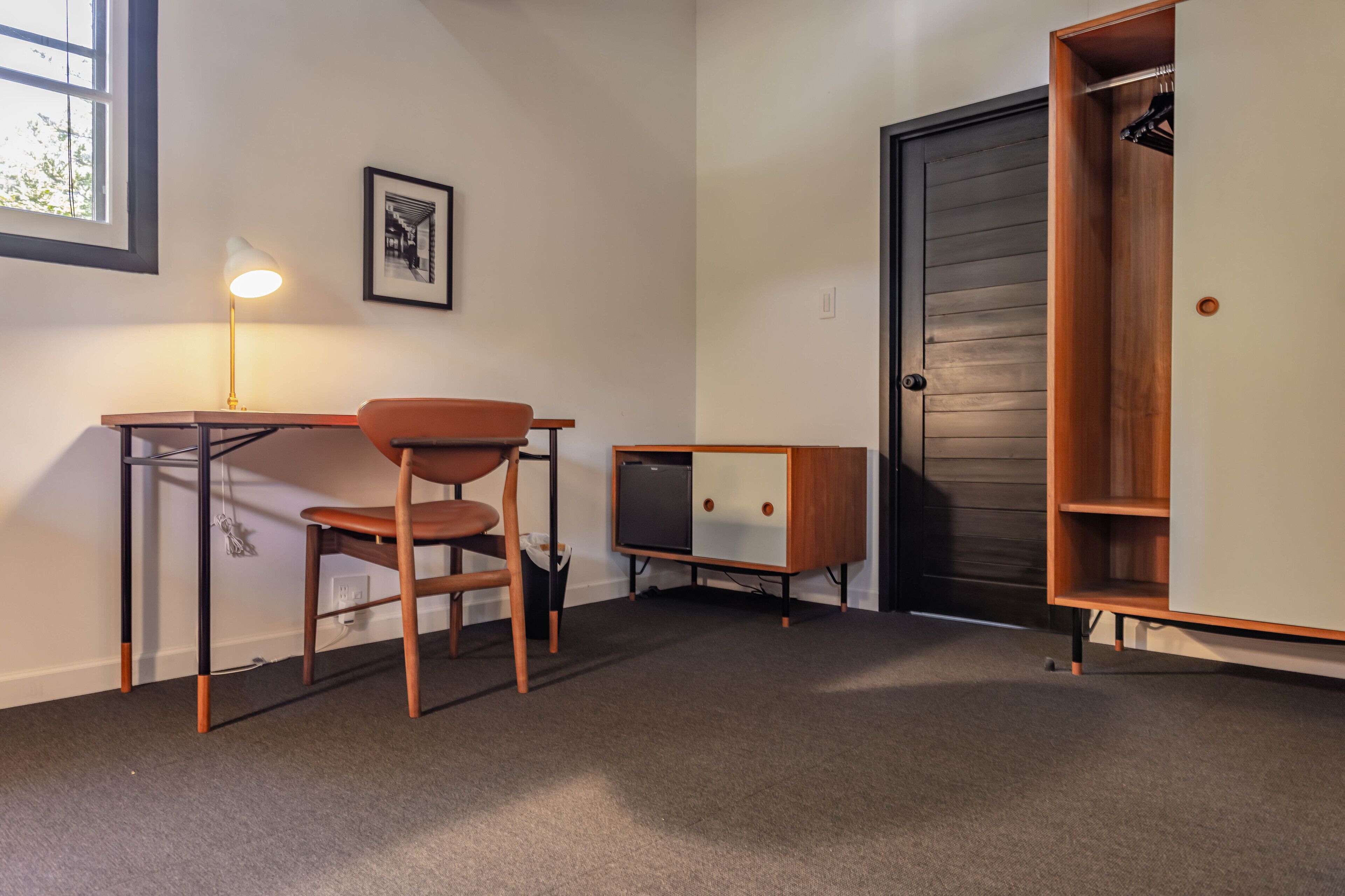 A compact room with a desk, chair, and a small cabinet.