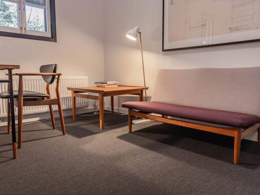 Una habitación con un escritorio de madera, una silla, un sofá y una lámpara de pie.