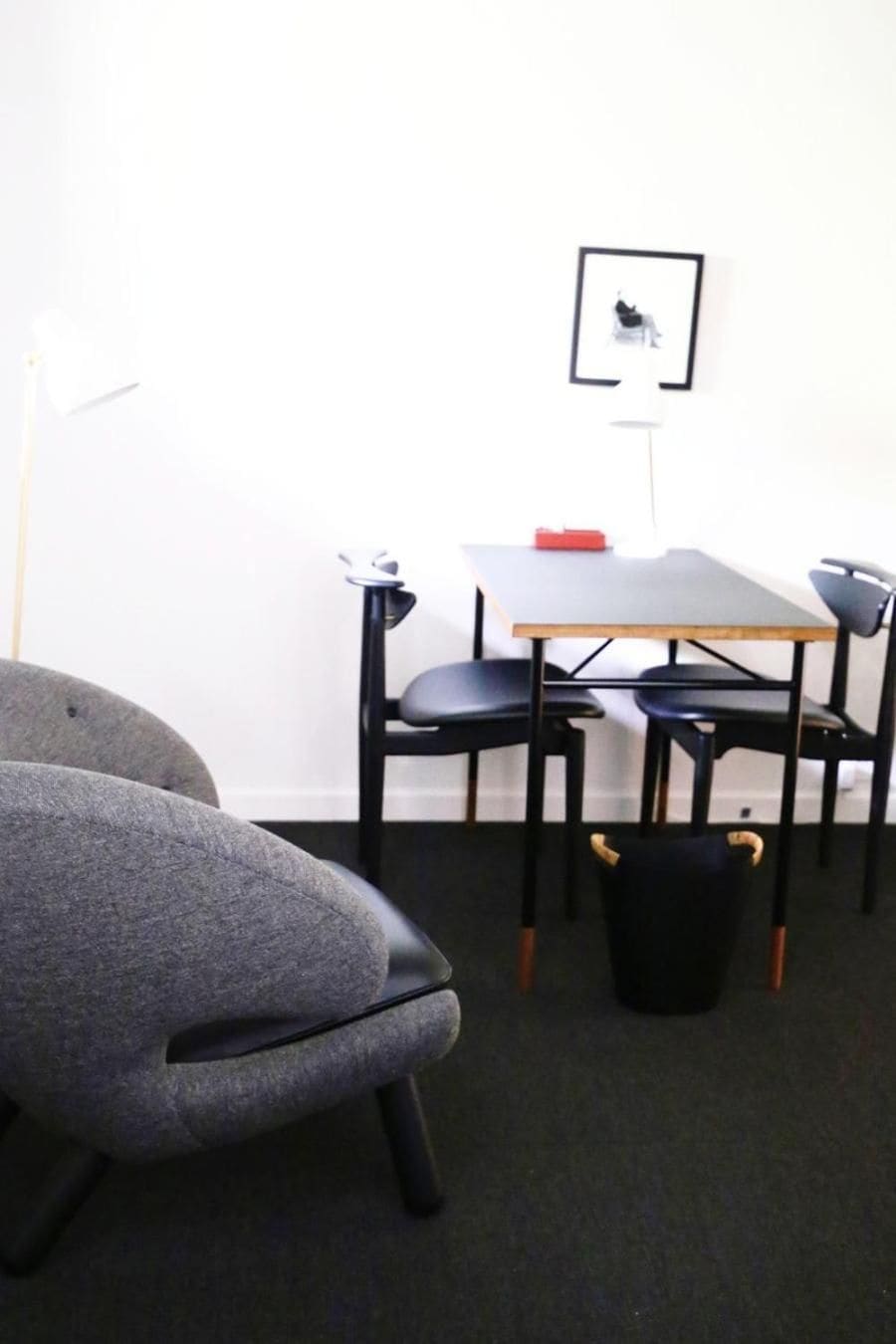Una habitación con una mesa y sillas, un cuadro en la pared y una silla negra con un asa amarilla.