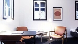 A room with a dark carpet, a wooden table, two chairs, a lamp, and a bed with a headboard. - House of Finn Juhl Hotel Hakuba (Hakuba)