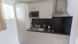 Cocina compacta con microondas, cafetera y lavamanos.