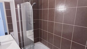 Un baño con bañera, ducha con cerramiento de vidrio y lavamanos blanco.